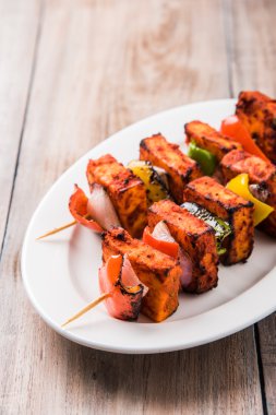 Paneer Tikka Kabab - Hint Tandoori peynir şişleri, malai paneer tikka / biber paneer malai paneer kabab, servis beyaz tabak Barbekü sopa ve renkli kırmızı biber ve soğan, yeşil sos ile