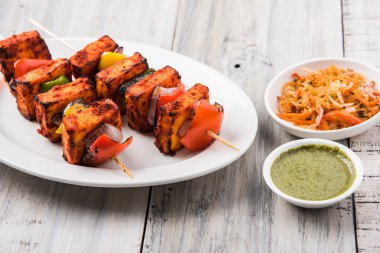 Paneer Tikka Kabab - Hint Tandoori peynir şişleri, malai paneer tikka / biber paneer malai paneer kabab, servis beyaz tabak Barbekü sopa ve renkli kırmızı biber ve soğan, yeşil sos ile