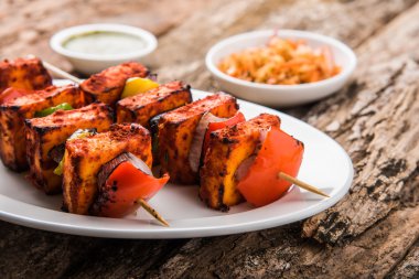 Paneer Tikka Kabab - Hint Tandoori peynir şişleri, malai paneer tikka / biber paneer malai paneer kabab, servis beyaz tabak Barbekü sopa ve renkli kırmızı biber ve soğan, yeşil sos ile