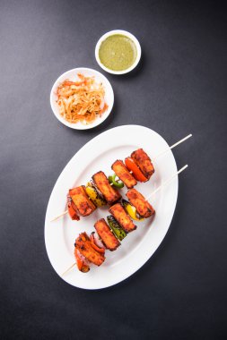 Paneer Tikka Kabab - Hint Tandoori peynir şişleri, malai paneer tikka / biber paneer malai paneer kabab, servis beyaz tabak Barbekü sopa ve renkli kırmızı biber ve soğan, yeşil sos ile