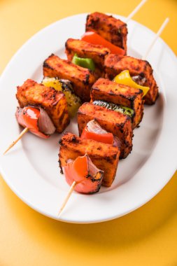 Paneer Tikka Kabab - Hint Tandoori peynir şişleri, malai paneer tikka / biber paneer malai paneer kabab, servis beyaz tabak Barbekü sopa ve renkli kırmızı biber ve soğan, yeşil sos ile