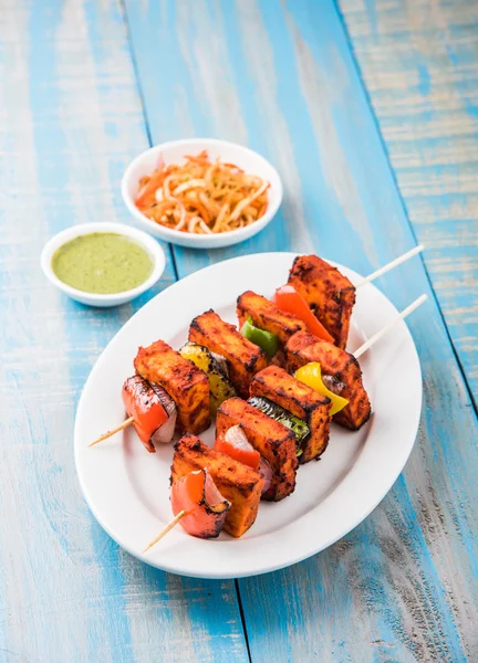 Paneer Tikka Kabab - Tandoori pinchos de queso indio, malai paneer tikka / malai paneer kabab, chile paneer servido en plato blanco con palo de barbacoa y colorido capsicum y cebolla, con salsa verde —  Fotos de Stock