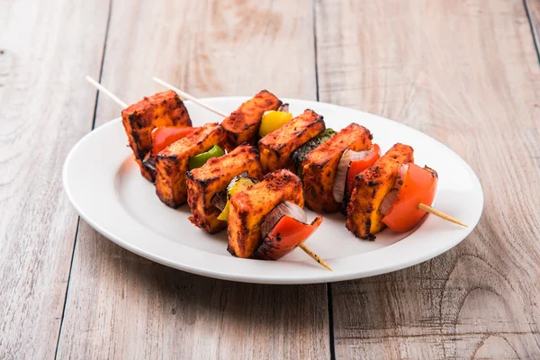 Paneer Tikka Kabab - Tandoori Indian cheese skewers, malai paneer tikka / malai paneer kabab, chilli paneer served in white plate with barbecue stick and colourful capsicum and onion, with green sauce — Stock Photo, Image