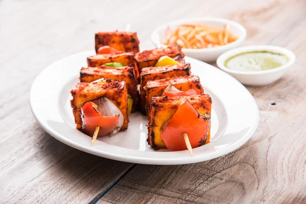 Paneer Tikka Kabab - Tandoori Indian cheese skewers, malai paneer tikka / malai paneer kabab, chilli paneer served in white plate with barbecue stick and colourful capsicum and onion, with green sauce — Stock Photo, Image