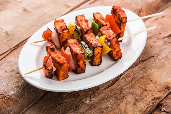 Paneer Tikka Kabab - Tandoori Indian cheese skewers, malai paneer tikka / malai paneer kabab, chilli paneer served in white plate with barbecue stick and colourful capsicum and onion, with green sauce — Stock Photo, Image