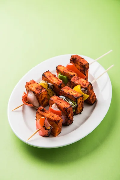 Paneer Tikka Kabab - Tandoori Indian cheese skewers, malai paneer tikka / malai paneer kabab, chilli paneer served in white plate with barbecue stick and colourful capsicum and onion, with green sauce — Stock Photo, Image