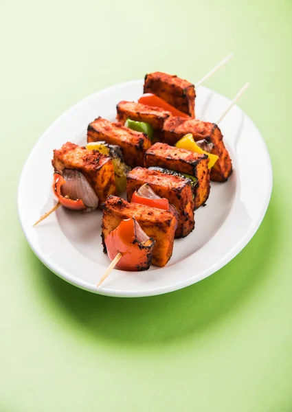 Paneer Tikka Kabab - Tandoori Indian cheese skewers, malai paneer tikka / malai paneer kabab, chilli paneer served in white plate with barbecue stick and colourful capsicum and onion, with green sauce — Stock Photo, Image