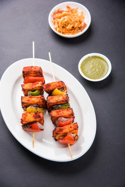 Paneer Tikka Kabab - Tandoori Indian cheese skewers, malai paneer tikka / malai paneer kabab, chilli paneer served in white plate with barbecue stick and colourful capsicum and onion, with green sauce — Stock Photo, Image