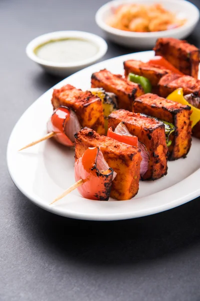 Paneer Tikka Kabab - Tandoori Indian cheese skewers, malai paneer tikka / malai paneer kabab, chilli paneer served in white plate with barbecue stick and colourful capsicum and onion, with green sauce — Stock Photo, Image