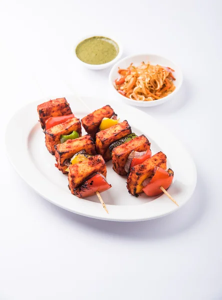 Paneer Tikka Kabab - Tandoori Indian cheese skewers, malai paneer tikka / malai paneer kabab, chilli paneer served in white plate with barbecue stick and colourful capsicum and onion, with green sauce — Stock Photo, Image