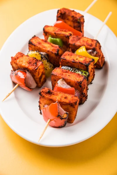 Paneer Tikka Kabab - Tandoori pinchos de queso indio, malai paneer tikka / malai paneer kabab, chile paneer servido en plato blanco con palo de barbacoa y colorido capsicum y cebolla, con salsa verde —  Fotos de Stock