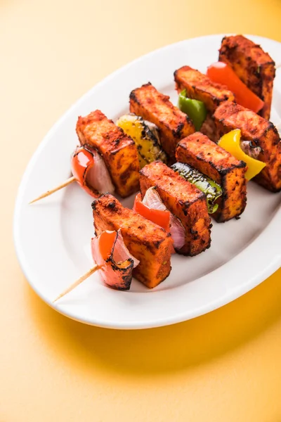 Paneer Tikka Kabab - Tandoori Indian cheese skewers, malai paneer tikka / malai paneer kabab, chilli paneer served in white plate with barbecue stick and colourful capsicum and onion, with green sauce — Stock Photo, Image