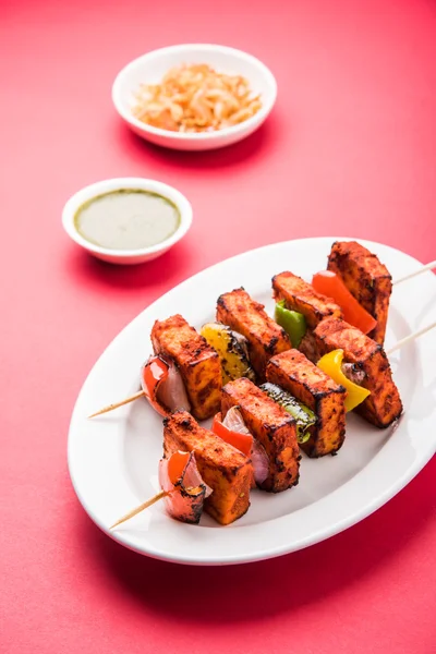 Paneer Tikka Kabab - Tandoori Indian cheese skewers, malai paneer tikka / malai paneer kabab, chilli paneer served in white plate with barbecue stick and colourful capsicum and onion, with green sauce — Stock Photo, Image