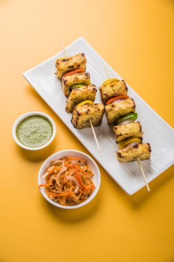 Paneer Tikka Kabab - Hint Tandoori peynir şişleri, malai paneer tikka / biber paneer malai paneer kabab, servis beyaz tabak Barbekü sopa ve yeşil sos, seçici odak ile