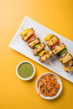 Paneer Tikka Kabab - Hint Tandoori peynir şişleri, malai paneer tikka / biber paneer malai paneer kabab, servis beyaz tabak Barbekü sopa ve yeşil sos, seçici odak ile
