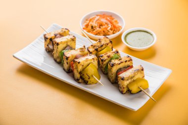 Paneer Tikka Kabab - Hint Tandoori peynir şişleri, malai paneer tikka / biber paneer malai paneer kabab, servis beyaz tabak Barbekü sopa ve yeşil sos, seçici odak ile