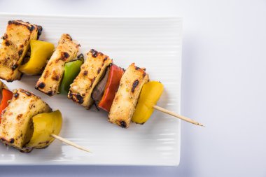 Paneer Tikka Kabab - Hint Tandoori peynir şişleri, malai paneer tikka / biber paneer malai paneer kabab, servis beyaz tabak Barbekü sopa ve yeşil sos, seçici odak ile