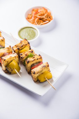 Paneer Tikka Kabab - Hint Tandoori peynir şişleri, malai paneer tikka / biber paneer malai paneer kabab, servis beyaz tabak Barbekü sopa ve yeşil sos, seçici odak ile