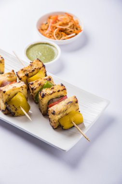 Paneer Tikka Kabab - Hint Tandoori peynir şişleri, malai paneer tikka / biber paneer malai paneer kabab, servis beyaz tabak Barbekü sopa ve yeşil sos, seçici odak ile