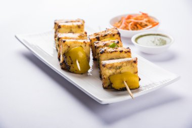 Paneer Tikka Kabab - Hint Tandoori peynir şişleri, malai paneer tikka / biber paneer malai paneer kabab, servis beyaz tabak Barbekü sopa ve yeşil sos, seçici odak ile