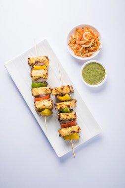 Paneer Tikka Kabab - Hint Tandoori peynir şişleri, malai paneer tikka / biber paneer malai paneer kabab, servis beyaz tabak Barbekü sopa ve yeşil sos, seçici odak ile