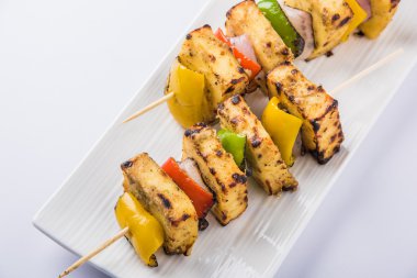 Paneer Tikka Kabab - Hint Tandoori peynir şişleri, malai paneer tikka / biber paneer malai paneer kabab, servis beyaz tabak Barbekü sopa ve yeşil sos, seçici odak ile