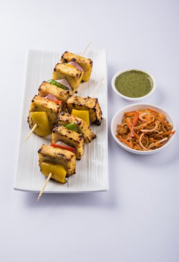 Paneer Tikka Kabab - Hint Tandoori peynir şişleri, malai paneer tikka / biber paneer malai paneer kabab, servis beyaz tabak Barbekü sopa ve yeşil sos, seçici odak ile