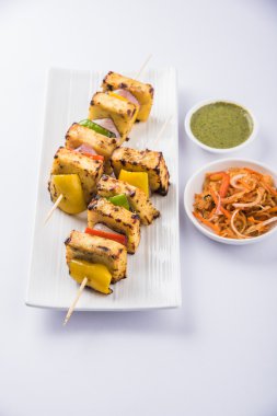 Paneer Tikka Kabab - Hint Tandoori peynir şişleri, malai paneer tikka / biber paneer malai paneer kabab, servis beyaz tabak Barbekü sopa ve yeşil sos, seçici odak ile