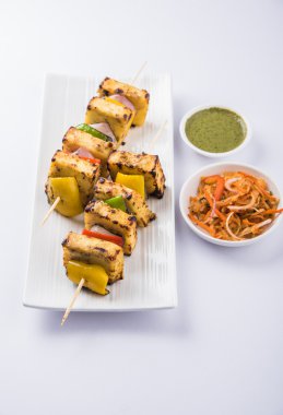 Paneer Tikka Kabab - Hint Tandoori peynir şişleri, malai paneer tikka / biber paneer malai paneer kabab, servis beyaz tabak Barbekü sopa ve yeşil sos, seçici odak ile