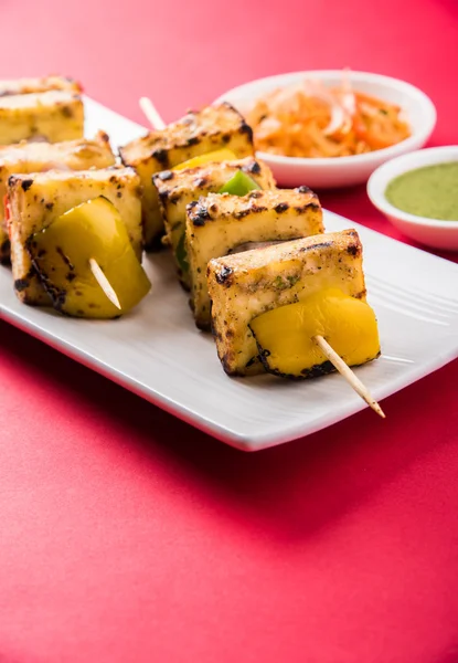 Paneer Tikka Kabab - Tandoori Indian cheese skewers, malai paneer tikka / malai paneer kabab, chilli paneer served in white plate with barbecue stick and colourful capsicum and onion, with green sauce — Stock Photo, Image