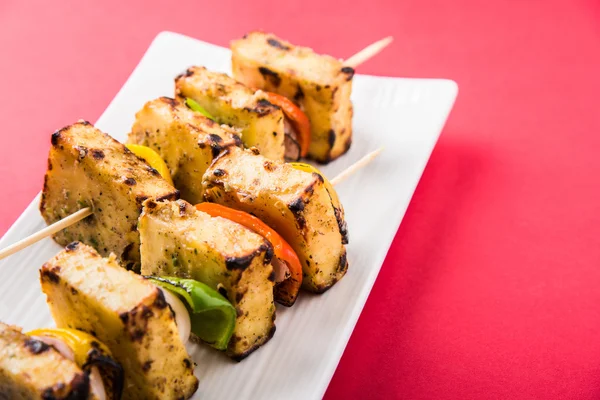 Paneer Tikka Kabab - Tandoori Indian cheese skewers, malai paneer tikka / malai paneer kabab, chilli paneer served in white plate with barbecue stick and colourful capsicum and onion, with green sauce — Stock Photo, Image