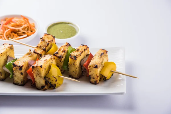 Paneer Tikka Kabab - Tandoori Indian cheese skewers, malai paneer tikka / malai paneer kabab, chilli paneer served in white plate with barbecue stick and green sauce, selective focus — Stock Photo, Image