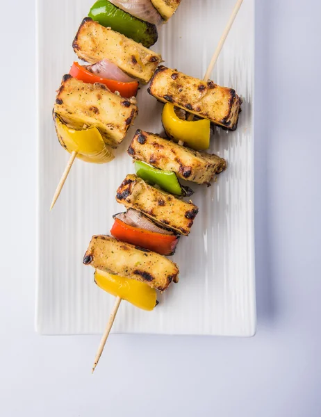 Paneer Tikka Kabab - Tandoori Indian cheese skewers, malai paneer tikka / malai paneer kabab, chilli paneer served in white plate with barbecue stick and green sauce, selective focus — Stock Photo, Image