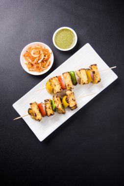 Paneer Tikka Kabab - Hint Tandoori peynir şişleri, malai paneer tikka / biber paneer malai paneer kabab, servis beyaz tabak Barbekü sopa ve yeşil sos, seçici odak ile