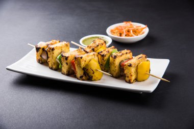 Paneer Tikka Kabab - Hint Tandoori peynir şişleri, malai paneer tikka / biber paneer malai paneer kabab, servis beyaz tabak Barbekü sopa ve yeşil sos, seçici odak ile