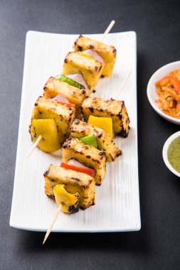 Paneer Tikka Kabab - Hint Tandoori peynir şişleri, malai paneer tikka / biber paneer malai paneer kabab, servis beyaz tabak Barbekü sopa ve yeşil sos, seçici odak ile