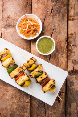 Paneer Tikka Kabab - Hint Tandoori peynir şişleri, malai paneer tikka / biber paneer malai paneer kabab, servis beyaz tabak Barbekü sopa ve yeşil sos, seçici odak ile