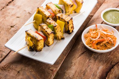 Paneer Tikka Kabab - Hint Tandoori peynir şişleri, malai paneer tikka / biber paneer malai paneer kabab, servis beyaz tabak Barbekü sopa ve yeşil sos, seçici odak ile
