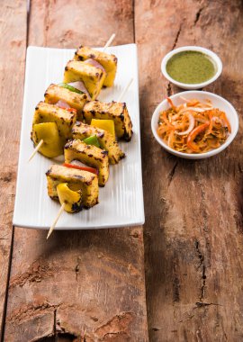 Paneer Tikka Kabab - Hint Tandoori peynir şişleri, malai paneer tikka / biber paneer malai paneer kabab, servis beyaz tabak Barbekü sopa ve yeşil sos, seçici odak ile