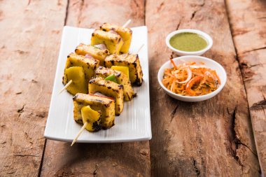 Paneer Tikka Kabab - Hint Tandoori peynir şişleri, malai paneer tikka / biber paneer malai paneer kabab, servis beyaz tabak Barbekü sopa ve yeşil sos, seçici odak ile