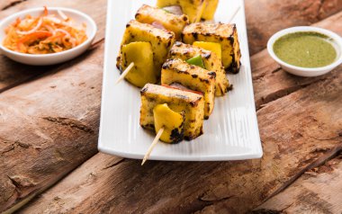 Paneer Tikka Kabab - Hint Tandoori peynir şişleri, malai paneer tikka / biber paneer malai paneer kabab, servis beyaz tabak Barbekü sopa ve yeşil sos, seçici odak ile