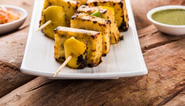 Paneer Tikka Kabab - Hint Tandoori peynir şişleri, malai paneer tikka / biber paneer malai paneer kabab, servis beyaz tabak Barbekü sopa ve yeşil sos, seçici odak ile