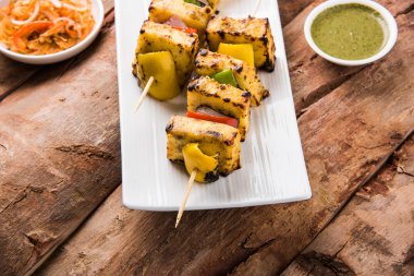 Paneer Tikka Kabab - Hint Tandoori peynir şişleri, malai paneer tikka / biber paneer malai paneer kabab, servis beyaz tabak Barbekü sopa ve yeşil sos, seçici odak ile