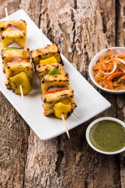 Paneer Tikka Kabab - Hint Tandoori peynir şişleri, malai paneer tikka / biber paneer malai paneer kabab, servis beyaz tabak Barbekü sopa ve yeşil sos, seçici odak ile
