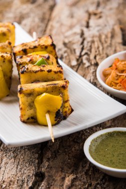 Paneer Tikka Kabab - Hint Tandoori peynir şişleri, malai paneer tikka / biber paneer malai paneer kabab, servis beyaz tabak Barbekü sopa ve yeşil sos, seçici odak ile