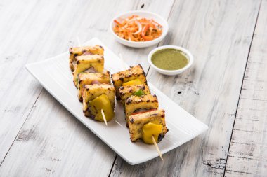 Paneer Tikka Kabab - Hint Tandoori peynir şişleri, malai paneer tikka / biber paneer malai paneer kabab, servis beyaz tabak Barbekü sopa ve yeşil sos, seçici odak ile