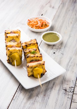 Paneer Tikka Kabab - Hint Tandoori peynir şişleri, malai paneer tikka / biber paneer malai paneer kabab, servis beyaz tabak Barbekü sopa ve yeşil sos, seçici odak ile