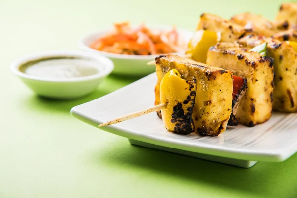 Paneer Tikka Kabab - Espetos de queijo indiano Tandoori, paneer malai tikka / paneer malai kabab, paneer chilli servido em placa branca com pau de churrasco e molho verde, foco seletivo — Fotografia de Stock