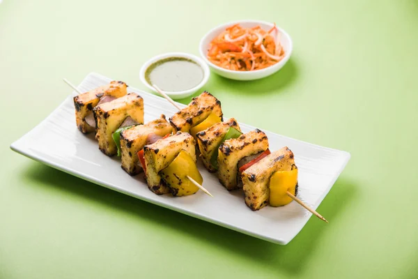 Paneer Tikka Kabab - Tandoori Indian cheese skewers, malai paneer tikka / malai paneer kabab, chilli paneer served in white plate with barbecue stick and green sauce, selective focus — Stock Photo, Image