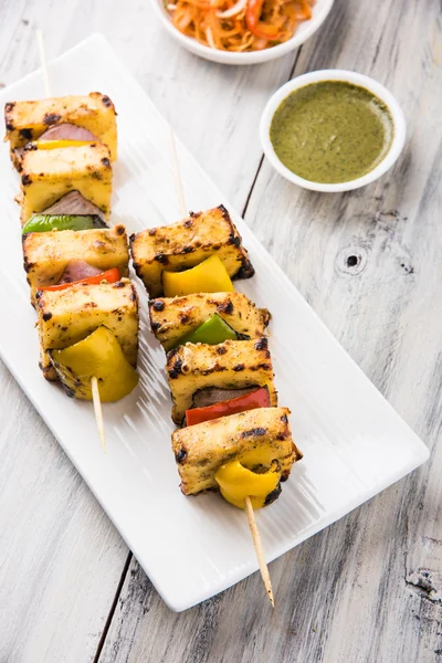 Paneer Tikka Kabab - Tandoori pinchos de queso indio, malai paneer tikka / malai paneer kabab, chile paneer servido en plato blanco con palo de barbacoa y salsa verde, enfoque selectivo —  Fotos de Stock